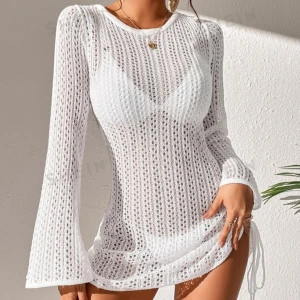 Vit stickad klänning - En vit stickad klänning med långärmad design och öppen rygg. Klänningen har en tight passform och är kort i längden. Den är tillverkad av ett stickat material som ger en luftig och bekväm känsla. Beachdress!