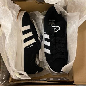 Adidas campus 00s black - Säljer ett par helt oanväda adidas campus 00s black med prislappen kvar. Det ingår både svarta och vita skosnören. Köpte de för 1700kr