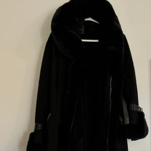 Pälsjacka  - Pälsjacka med bälte (inte äkta päls) Mocka material (pälsen kan man ta av) I mycket gott skick nästan som ny 