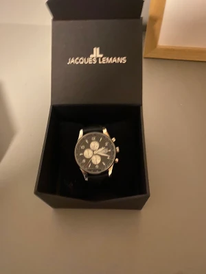 Jacques Leman - Klocka säljes några år gammal men använd väldigt sparsamt , är i bra skick ! Läderarmband , behöver bytas batteri 