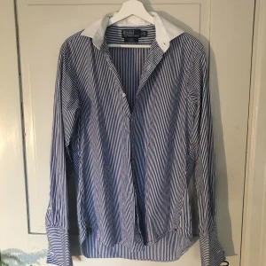 Ralph Lauren skjorta - Ralph Lauren skjorta med mörkblåa och vita ränder. Bra skick utan några defekter. Nypris: 1400. Storleken är som en lite större L. Hör av dig om du har några fler frågor!!