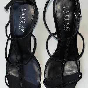 Ralph Lauen Klackar - Jag säljer mina svarta Ralph Lauren klackar eftersom jag har alldeles för många klackar. De är storlek 37, passar även 36,6. Remmar i tyg och strass, klack 9cm. Nypris: 1400kr Mitt pris: 500kr