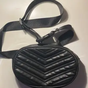 En Axel väska som är svart.
