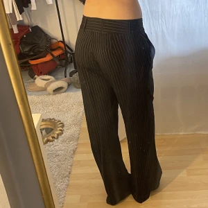 Randiga kostymbyxor  - Randiga kostymbyxor som på mig sitter loose och Low waist. Är strl 42 (L) men jag har sytt in midjan så sitter mer som 40 (M). Jag är 175 och de är väldigt långa på mig.