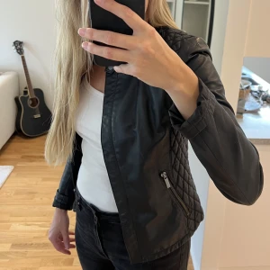 Skinnjacka  - Snygg bikerjacka från ZARA i skinimitation, mer dressad och slim i modellen, snyggt med linne eller t-shirt under. Superfint skick förutom en väldigt liten repa bak i nacken, strl XS.