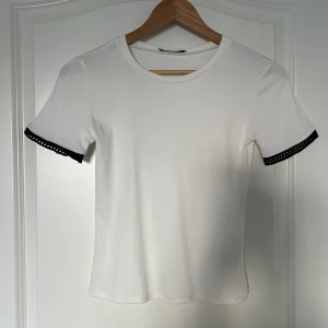 vit t-shirt med svarta detaljer  - en jätte fin tshirt från zara, använd några få gånger och är som ny. kommer inte till någon användg därför jag väljer att sälja den💗
