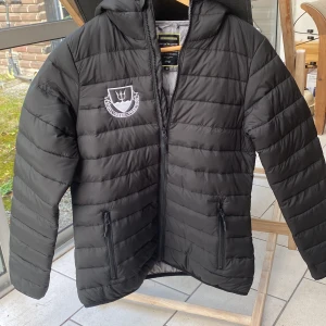 Jacka från Poseidon simklubben i Lund, storlek 38. - Sparsamt använd svart jacka från simklubben Poseidon i Lund. Icke-avtagbar luva. Storlek 38. Polyester 100%.
