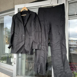 Massimo Dutti linnekostym - Byxor och kavaj i svart linne från Massimo Dutti, använda endast ett fåtal gånger. Båda delar storlek 42.  Byxorna har korta slits i anklarna på sidorna.  Rynkiga pga har varit nedpackade. 
