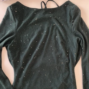 Klänning  - Säljer denna eftertraktade gröna glittriga klänningen med öppen rygg, obs! Färgen är som på bild 2