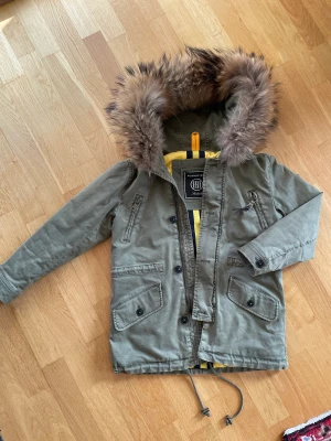 Blonde No. 8 höst/vinterjacka - Superfin höst/vinterjacka ifrån Blonde No. 8 i stl 8 y sparsamt använd. Pälsluvan går att ta bort. Khaki. Finns I Åsa/Kungsbacka