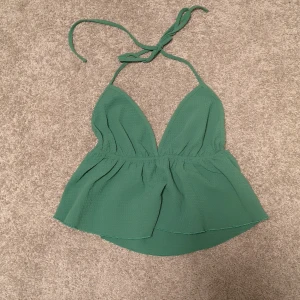 Halterneck-topp - En supersnygg halterneck-topp i en jättefin grön färg. Är i nyskick och i storlek S. 