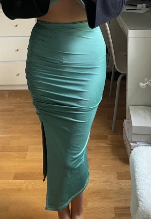 Grön kurvgivande kjol - Stretchig men tajt, lägger sig fint på kroppen. Storleken är S men stretchen ger utrymme till en M om man vill ha en tajtare form. Funkar även för XS om man skulle vilja ha den lösare
