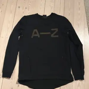 Det är en svart A-Z alltså Zlatans märkes tröja som är använd en del och har något litet håll (se bild) på båda sidor. Storlek 146-152. Men är väldigt bra och snygg.