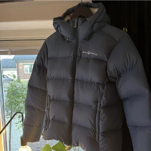 Blå sail racing jacka - En blå jacka från sail racing som inte kommer till användning mer. Jackan är inte använd speciellt mycket men tyvärr fått några små revor på framsidans nedre del (se bild 2). I övrigt är jackan i fint skick. Jackans passform har något smala ärmar☺️