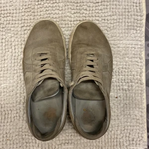 GRÅ ARIGATOS - Säljer mina grå AXEL ARIGATO skor! De är mycket använda, lite missfärgad men bra skick! De är en litet hål på undersidan av skon men det ser man ju inte på! Storlek 43!