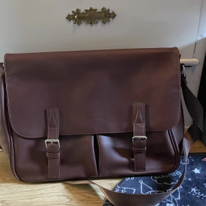 Axelväska  - Säljer denna då jag inte har någon användning för den❤️Den är i en fin burgundy färg, det finns 2 fickor med dragkjedja och 4 öppna fickor ( 2 stora på utsidan 2 små på insidan) Den är rätt stor så du får plats med dator och mycke mer❤️