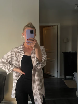 Oversized skjorta - Oversized skjorta från Lindex, beige/vit-randig. Så snygg att ha både över en outfit i sommar eller stängd till byxor mer uppklätt.