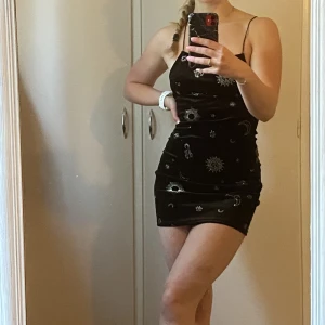 Mini-klänning - Svart mini-klänning med glittriga detaljer och en öppen rygg. Använd ca 2-3 ggr, inget slitage.