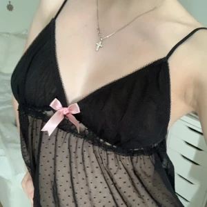 Svart fest topp med rosett - Svart lingerie topp med rosa rosett. Nästan aldrig använt. Storlek M men passar även XS och S.