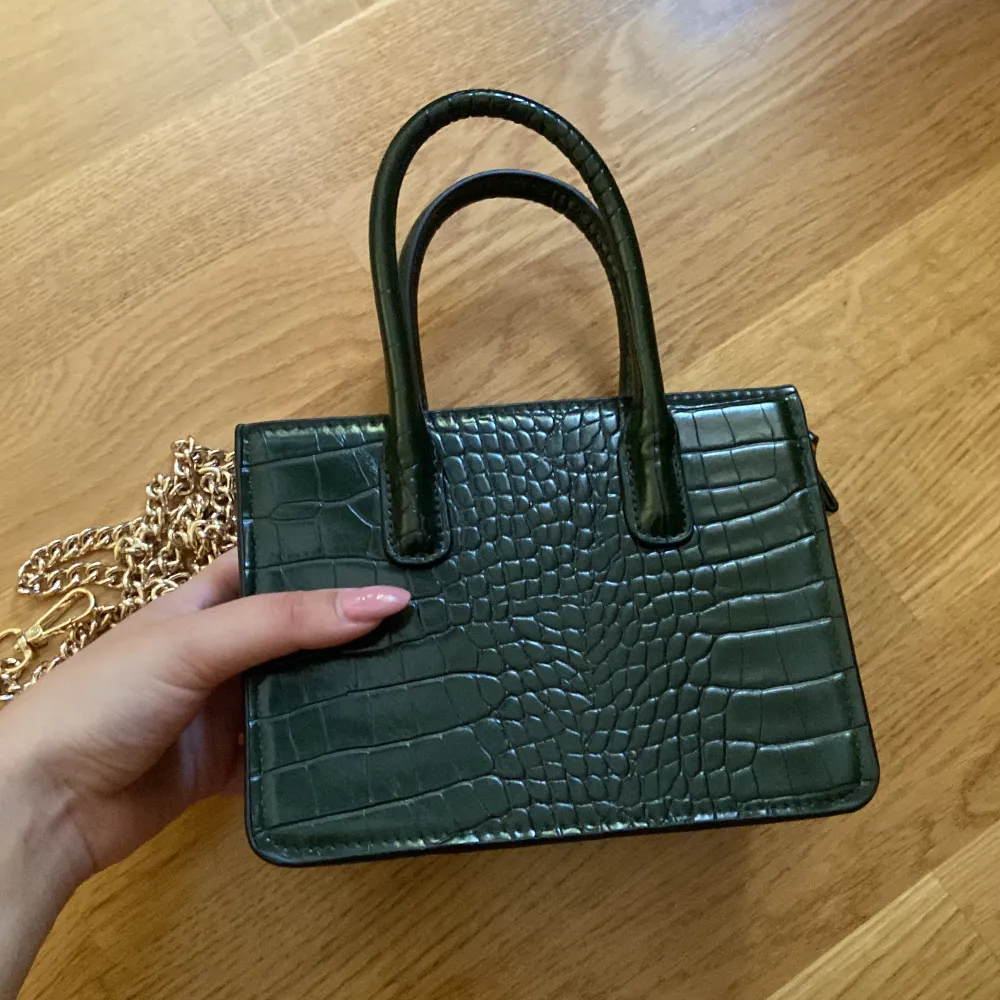 En gullig liten, grön väska från H&M med tillhörande guldig kedja för att bära över axeln💖💓. Väskor.