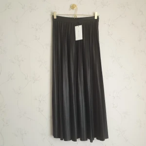 Zara svart plisserad maxikjol  - ☀️FÖRST TILL KVARN!☀️ Svart plisserad maxikjol i skinnimitation från Zara. Ny i nyskick med prislapp, endast testad aldrig använd. Lite stretchig i tyget. Storlek XS, men kan även passa en S, om man har en lite mindre midja. Kan skicka mått vid intresse.