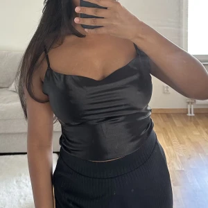 Svart satintopp  - En superfin svart satintopp från shein, säljs då jag inte längre får användning för den!(Dragkedja vid sidan så den går lättare att sätta på) 