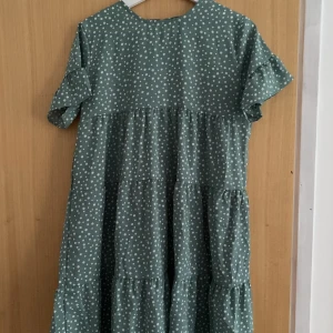 Sommarklänning - En grön sval sommarklänning med vita prickar. Oanvänd så i nytt skick, strl. S. Färgen gör sig mest rättvis på sista bilden.
