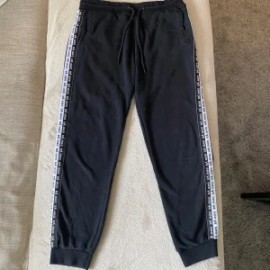 SVARTA MJUKISBYXOR - Svarta streetmjukisbyxor från FB sister. Insydda tyg stripes på sidorna. Väl använda, lite noppiga men väldigt bekväma. Stor storlek men passar som M.