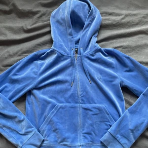 Blå juicy couture kofta - Säljer min blåa juicy couture kofta på grund av att jag inte använder den. Den är i bra skick och använd 2 gånger, tröjan är i storlek M men passar på mig som är 162 cm lång 