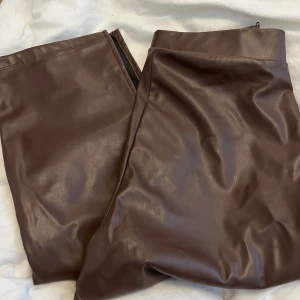 Skinnbyxor bruna - Säljer dessa Skinnbyxor från Nelly då de tyvärr är för små för mig. Endast testade och därav är lappen borta, men aldrig använda. Har slits vid båda fötterna och dragkedja. Smickrande passform. Självklart inte äkta skinn. 