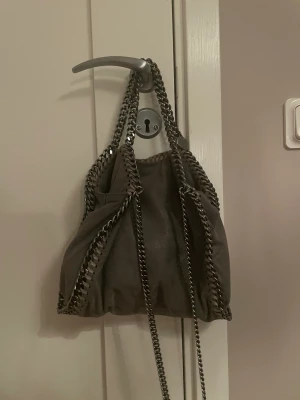Äkta stella väska - säljer nu min snygga och älskade stella mccartney väska. Small i grå, med silver detaljer . I fint men använt skick, ingen rost på kedjorna, men två små fläckar på sidan som inte syns (fråga om bild)❤️ Hoppas den hittar ett nytt hem där den blir älskad.