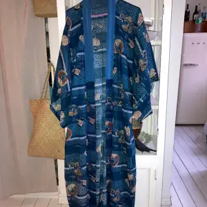 En otroligt fin kimono i blåa och gröna färger. Vida ärmar och rak passform. Kan bäras upp till XL. Känns väldigt lyxig!