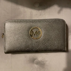 Michael kors plånbok silvrig guld - Kvaliteten är bra och den har inga defekter. Massa fack och effektiv design. Tror den är äkta men har inte kvar något kvitto så vet inte.