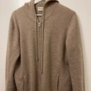 Kashmir hoodie med zip - Kashmir hoodie från soft goat, använd för ett tag sedan men nu inte på länge. Storleken är L men den passar även M. Skick: 9/10, pyttelitet hål vid ärmen men det är inte märkbart överhuvudtaget. Beige/brun färg. 
