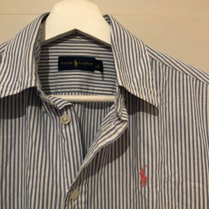 Ralph Lauren Skjorta - Ralph Lauren Skjorta med ljusblåa och vita ränder i bra skick utan några defekter! Skriv gärna om du har några frågor!!