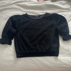 Svart glittrig topp - Jätte glittrig svart ganska genomskinlig topp perfekt till nyår. Den är använd fåtal gånger och är i nyskick. 