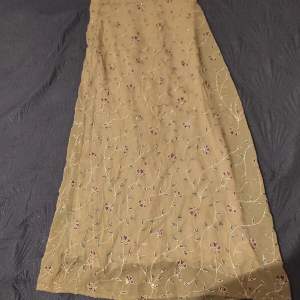 Jättefin gröngul lång kjol med glittrigt blommigt mönster. Det är ett mesh aktigt typg som är lite genomskinligt med tyg under. Supervacker😍