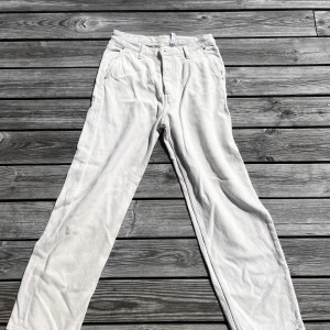 WeekDay tygbyxor  - Ett par beiga tygbyxor från weekDay i modellen Space. Använd ett fåtal gånger men i gott skick. Perfekt för sena sommarkvällar!  Storlek 28, passar om du är mellan 185-190 