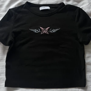 Svart t-shirt - Svart croppad t-shirt med litet tryck.