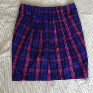 Rutig kjol från Monki  - Rutig kjol från Monki i storlek M som inte säljs längre, knappt använd och i bra skick frutom en söm (bild 3). Den är räfflad på framsidan och har dragkedja och knappar på baksidan. 