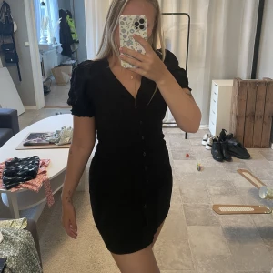 Klänning  - Klänning med knappar hela vägen, puffarmar och tightare i midjan 