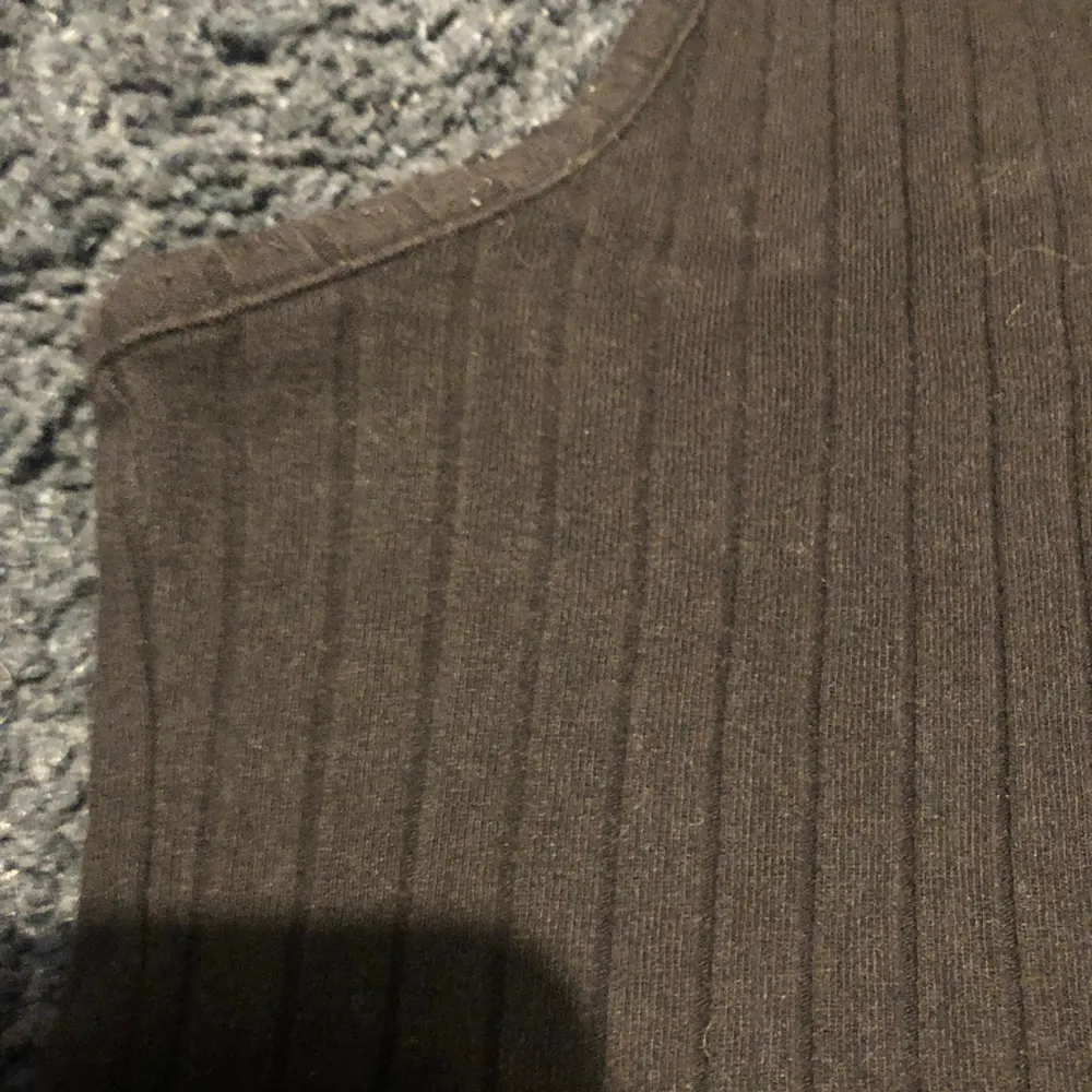 Svart ribbat linne, V ringning, stretchigt material, knappt använd, är helt svart i verkligheten (ser grå/brun ut på bild). Toppar.