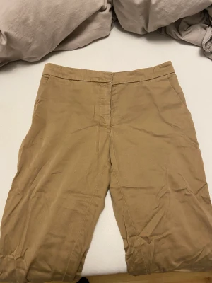 Kostymbyxor - Detta är ett par kostymbyxor som är beige/bruna. Byxorna kommer ringde till användning och därför säljer jag dom. Storleken står ej men dom är lite för små för mig som brukar ha 36. Dom är i bra skick. Priset kan diskuteras💕