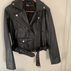 Svart Skinnjacka ZARA - Svart skinnjacka med snygga detaljer från Zara 🖤 Den är använd 2 gånger så  fortfarande som ny! Något mindre i storlek, passar XS/S/M beroende på passform 🫶🏼