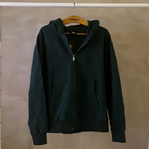 Stussy Zipup - En mörkgrön stussy zipup med klöver tryck på ryggen. 