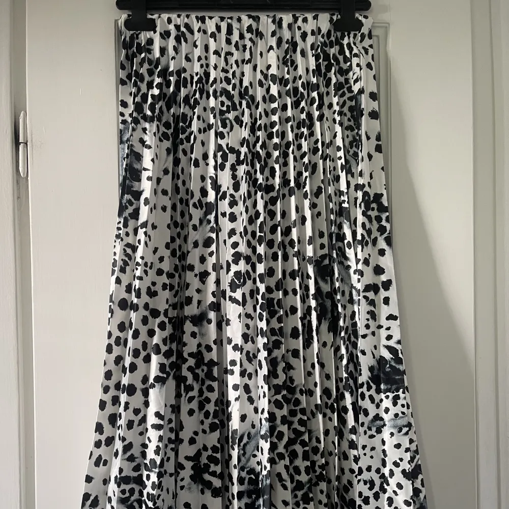 En lång plisserad kjol i vitt med svarta prickar som endast är använd 1 gång. Mycket bra skick och inga defekter. Skriv vid frågor💕. Kjolar.