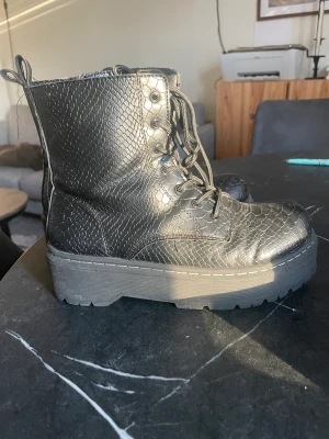 Boots i ormskinn  - Svara boots i ormskinns material, syntet. 