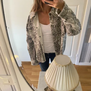 Denim jacka i orm mönster - Den här jackan i ungefär jeansmaterial, den är köpt på Zara och bara andvänd en gång. Den har  metall stenar som detalj, den är i väldigt fint skick. Jackan är i storlek S, den har längre bak än fram. Priset kan såklart diskuteras. 
