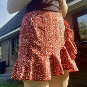 Röd kjol - Jättefin röd kjol med vita detaljer på ❤️ endast testad, säljer pga att den aldrig kommer till användning. Väldigt härligt tyg med blixtlås i sidan och knytning, perfekt nu till sommaren 🫶🏻☀️