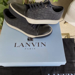 Lanvin Croc Embossed Low Sneaker - Hej, säljer ett par snygga Lanvin sneakers i mycket bra skick. Sparsamt använda och inga defekter. Unika med blå krokodilliknande mönster. Storlek 8 vilket motsvarar 42/43. Har dustbags från köp. Nypris runt 4000kr. Pris inte hugget i sten. Hör av dig!